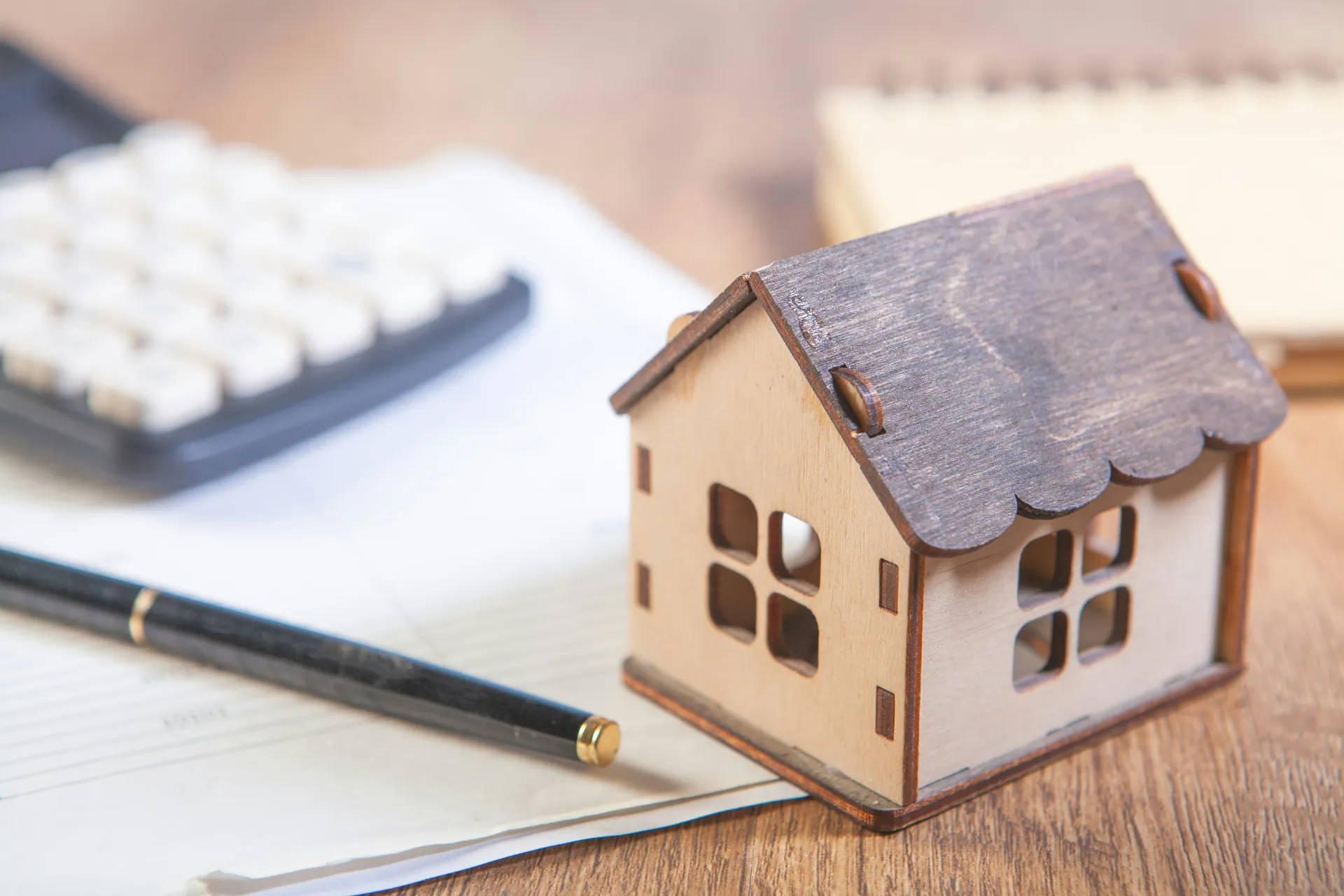 Maison en bois, stylo et calculatrice 
