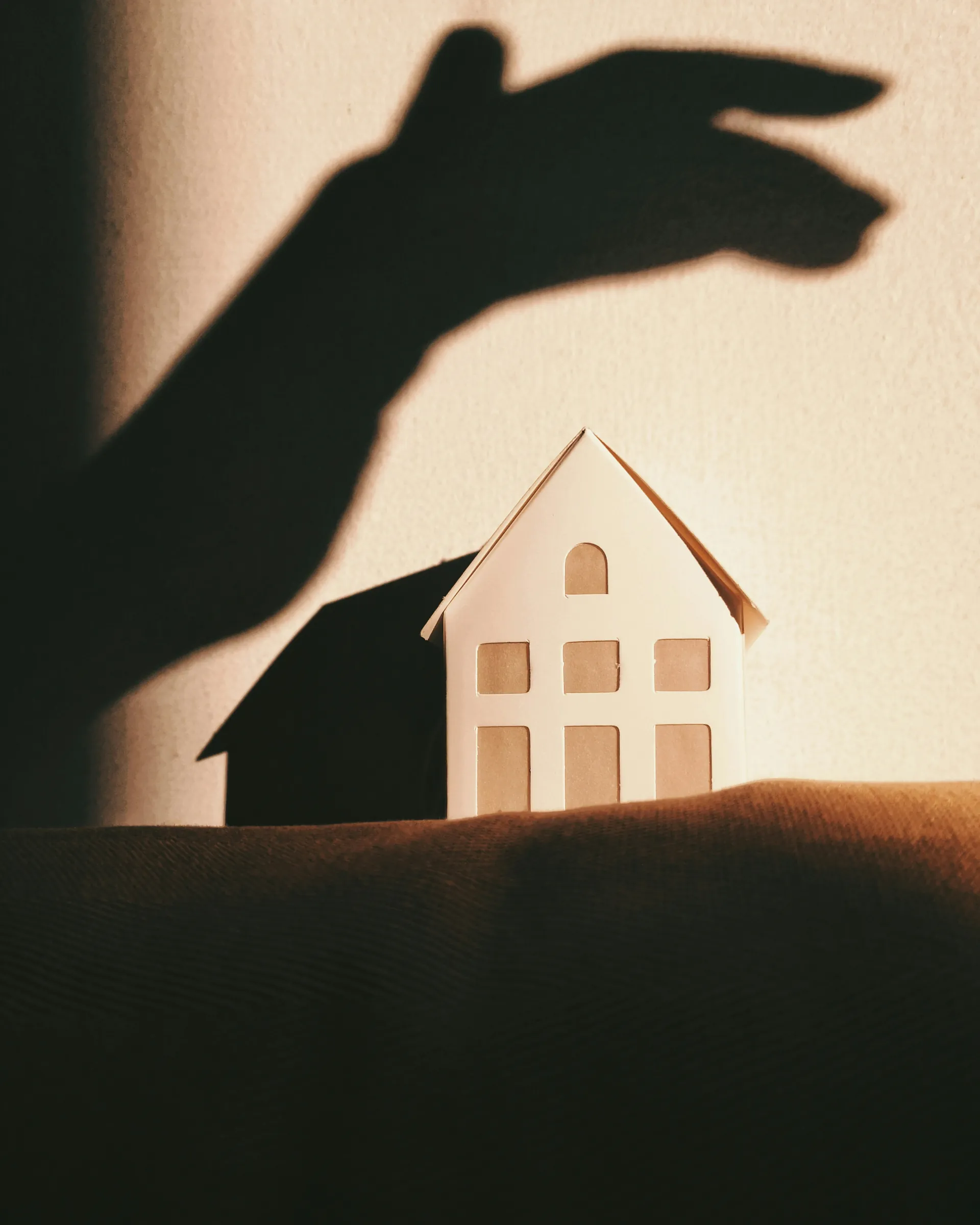 L'ombre d'une main avec une petite maison en bois