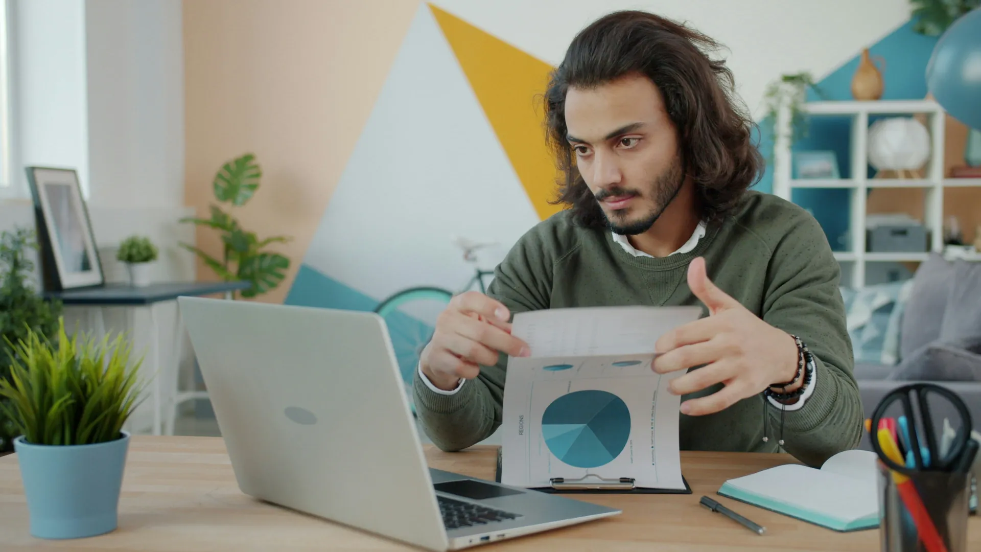 Monsieur devant un ordinateur et des graphique dans les mains
