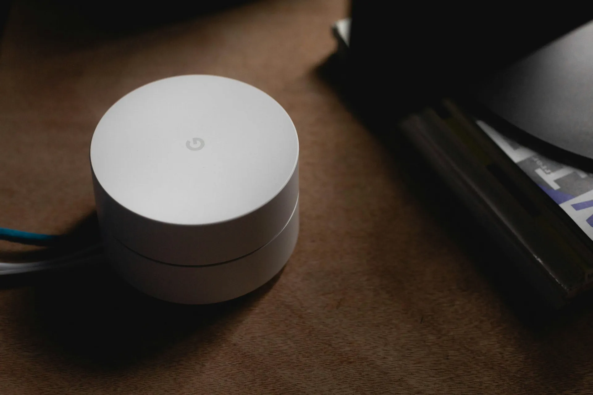 Routeur Google Wifi blanc posé sur une table en bois avec câbles connectés